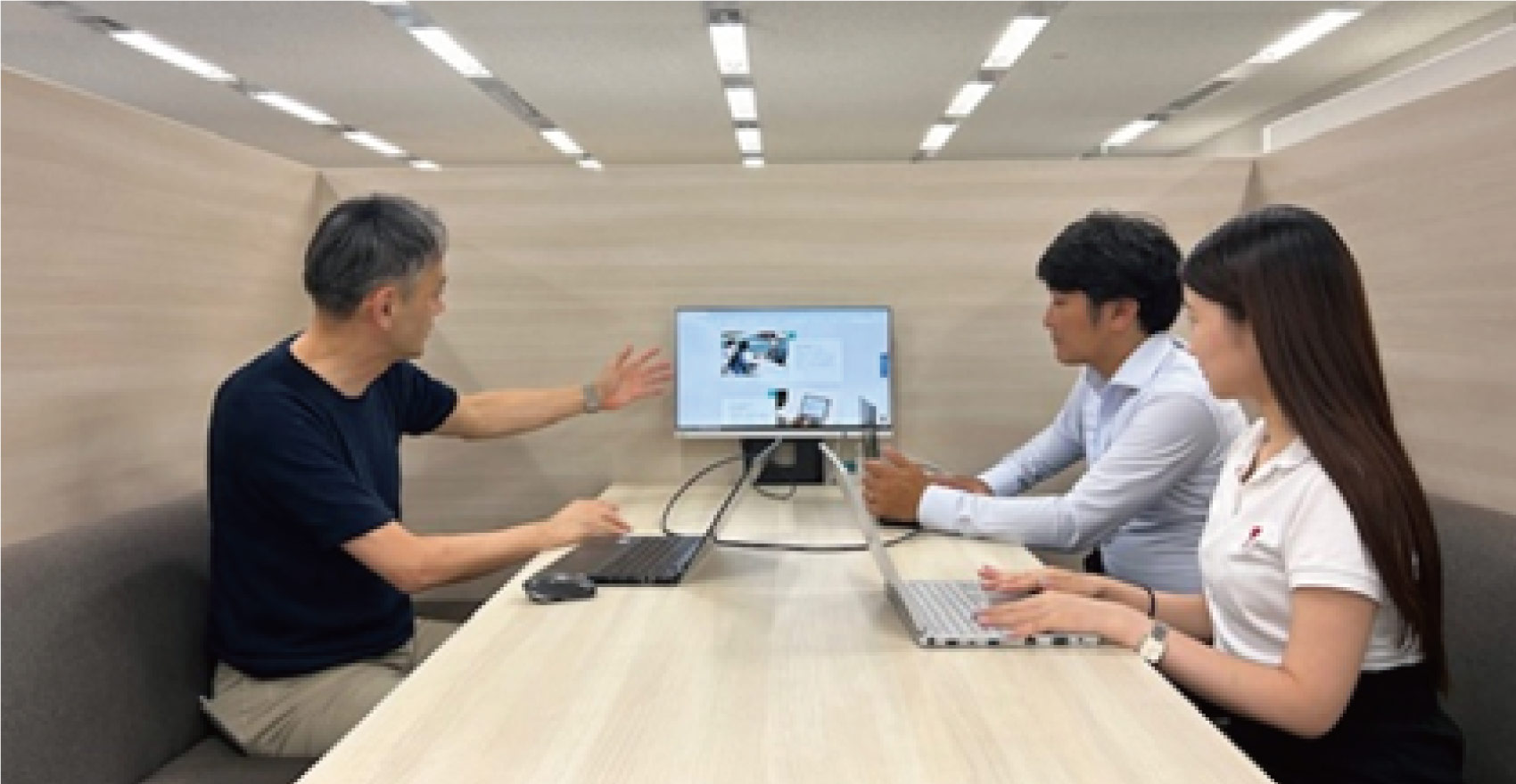 社員がPCとモニターを使いながら打ち合わせを行う様子