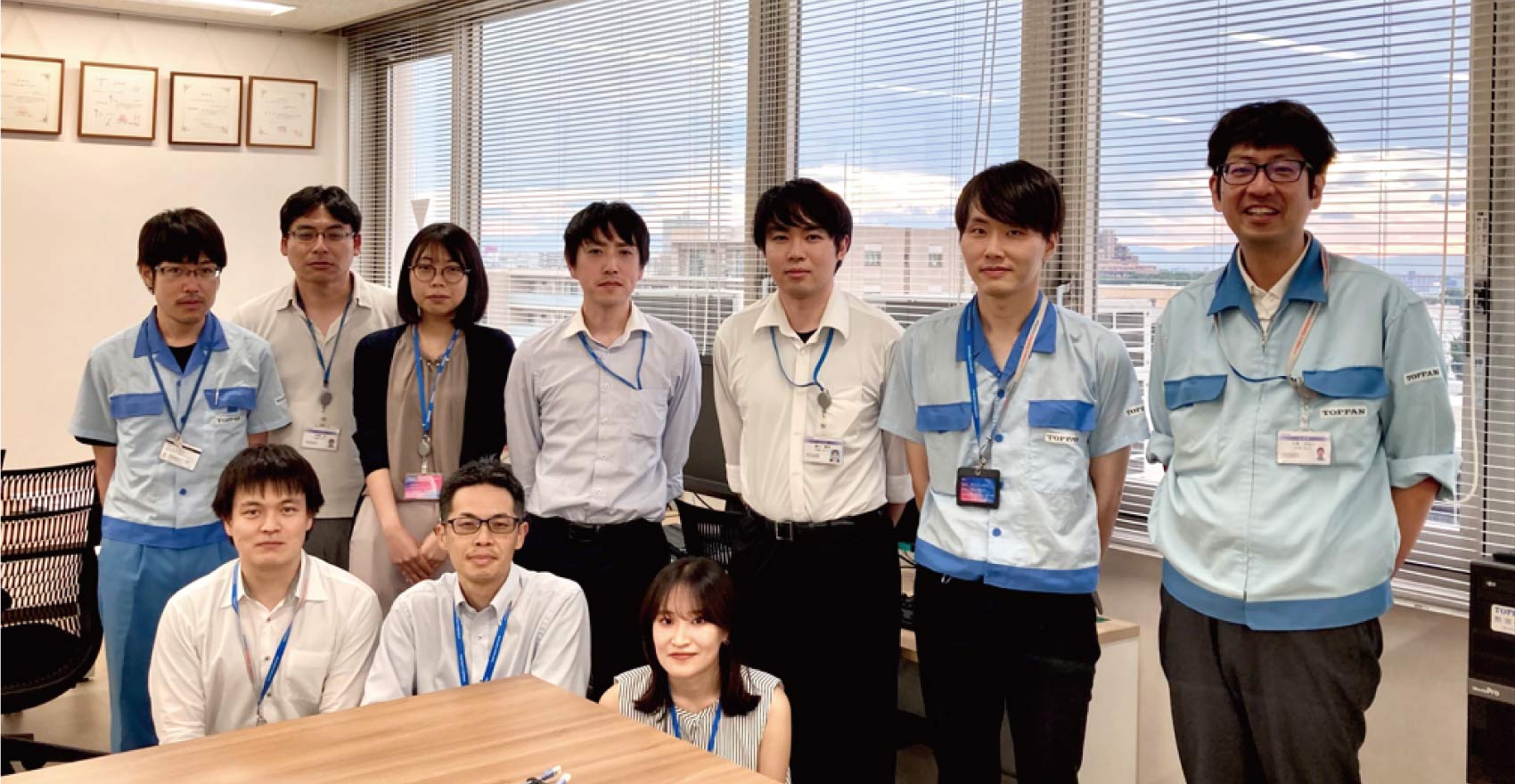 男性社員8名、女性社員2名の計10名が前後2列に並んだ形の集合写真
