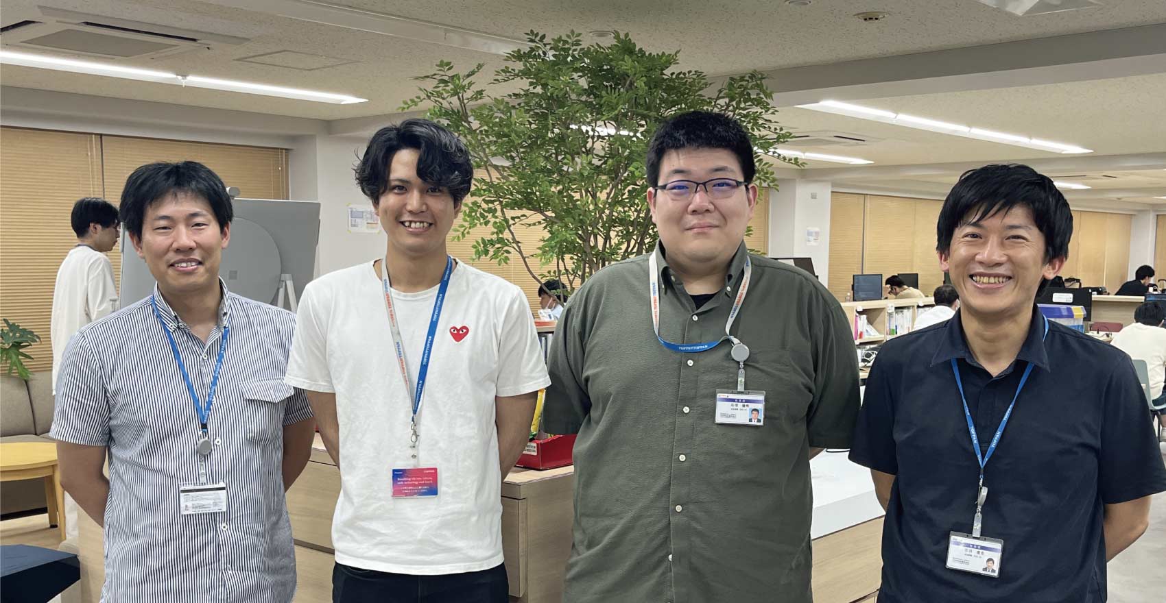 男性社員4名が正面を向いて並んで笑顔をむける様子