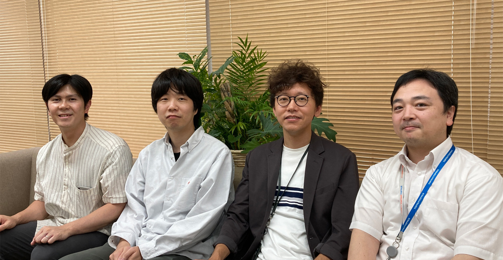 男性社員4名が正面を向いて並んで笑顔をむける様子