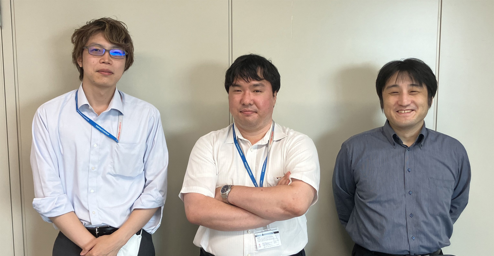 男性社員3名が正面を向いて並んで笑顔をむける様子