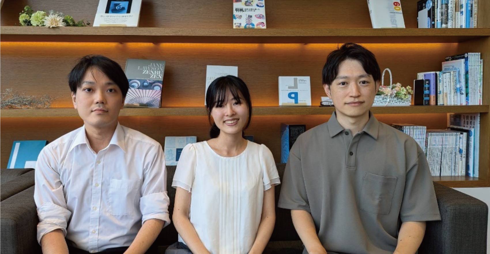 男性社員2名と女性社員1名が正面を向いて並んで笑顔をむける様子