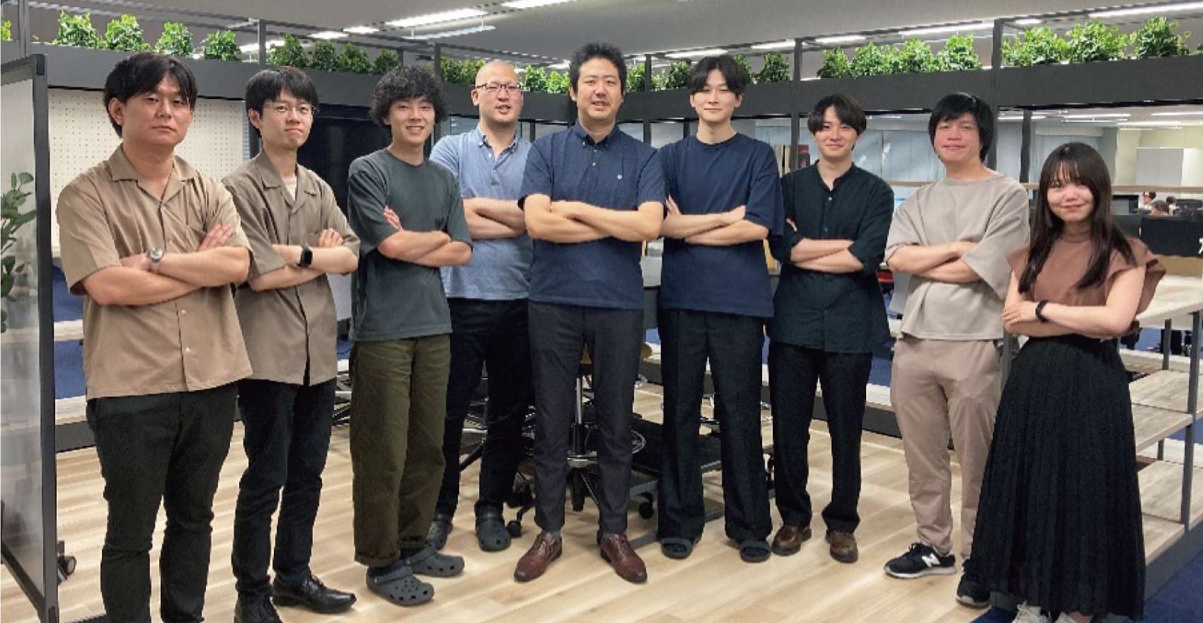 男性社員8名、女性社員1名の計9名が横1列に並んだ集合写真