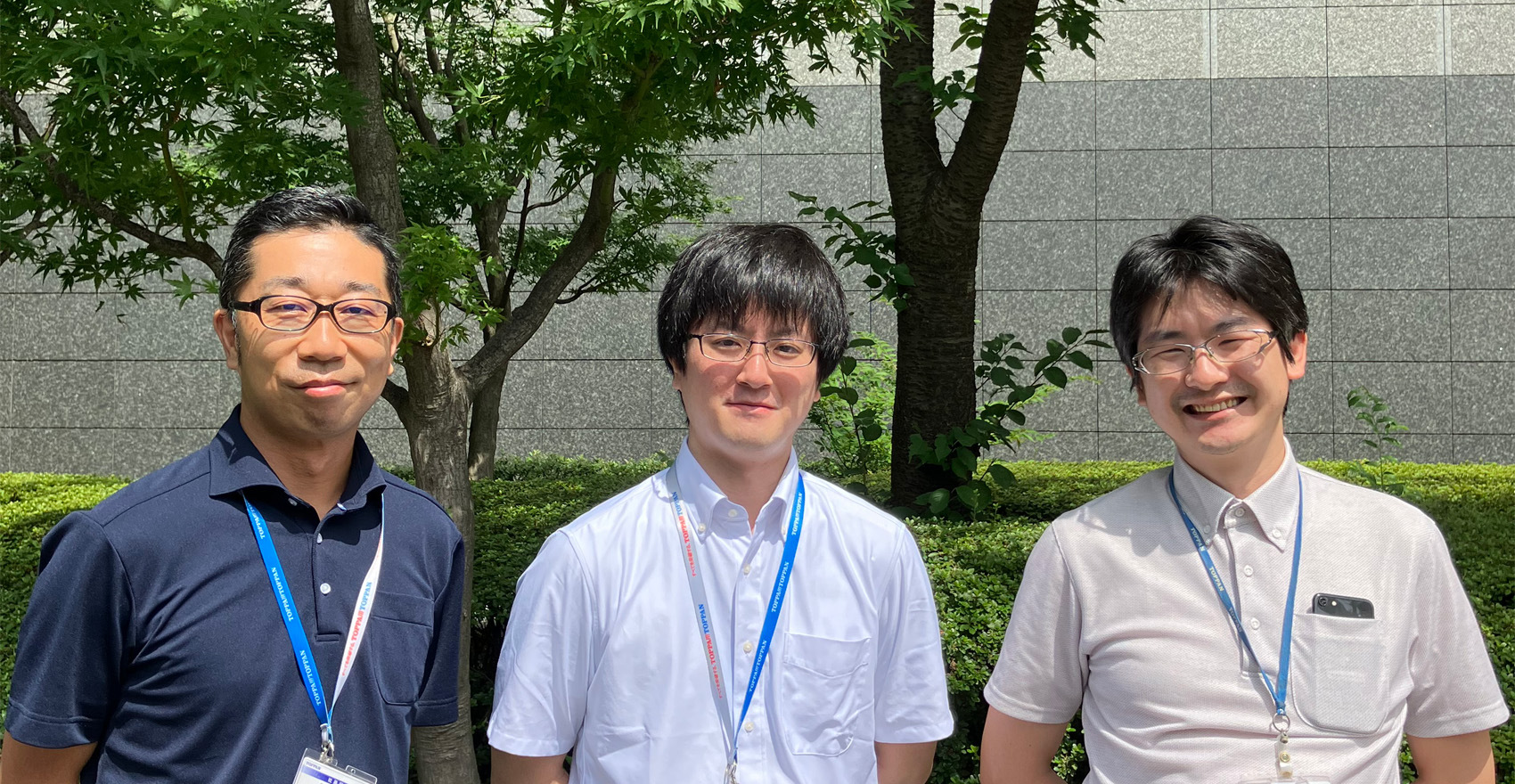 男性社員3名が正面を向いて並んで笑顔をむける様子
