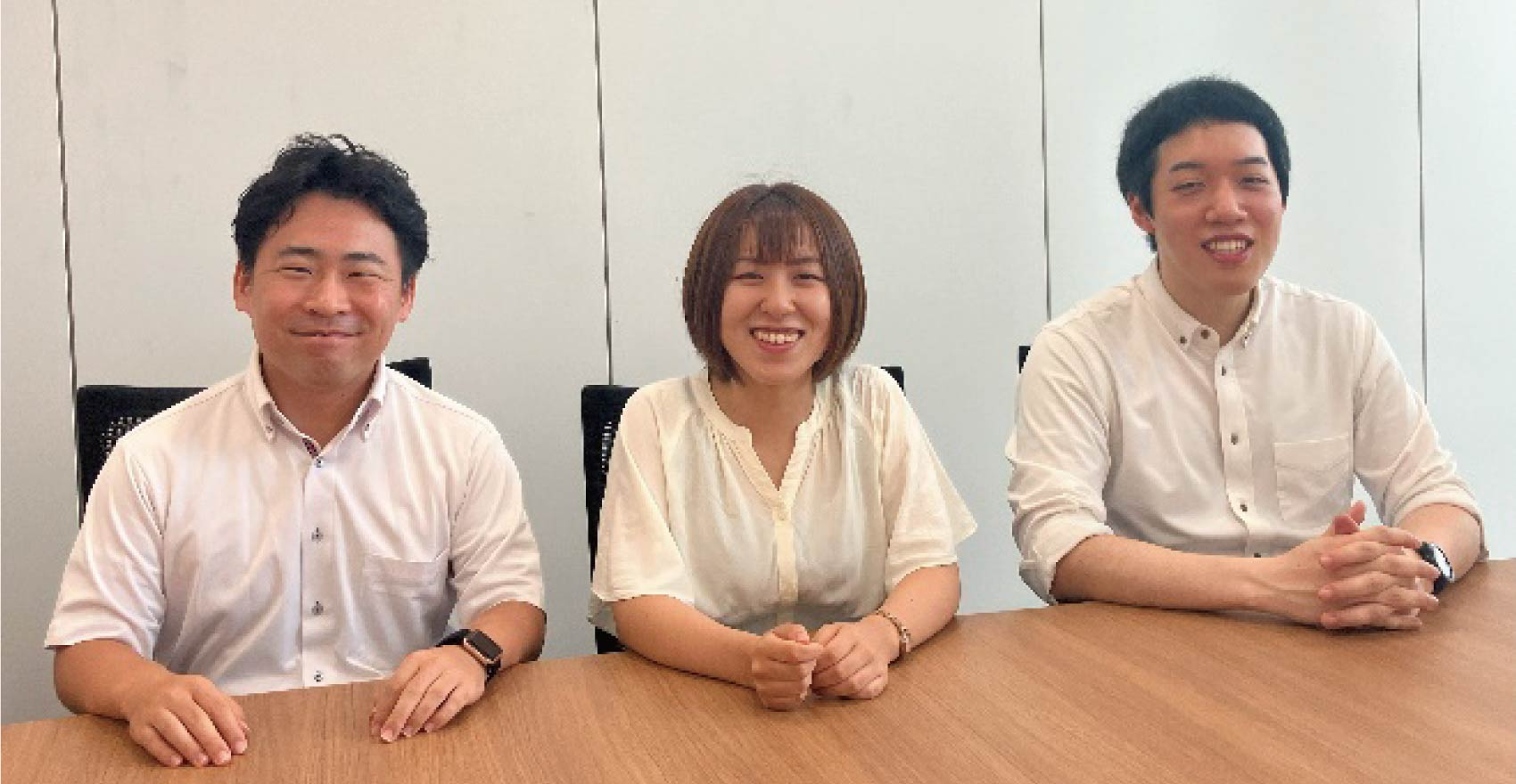 男性社員2名と女性社員1名が正面を向いて並んで笑顔をむける様子
