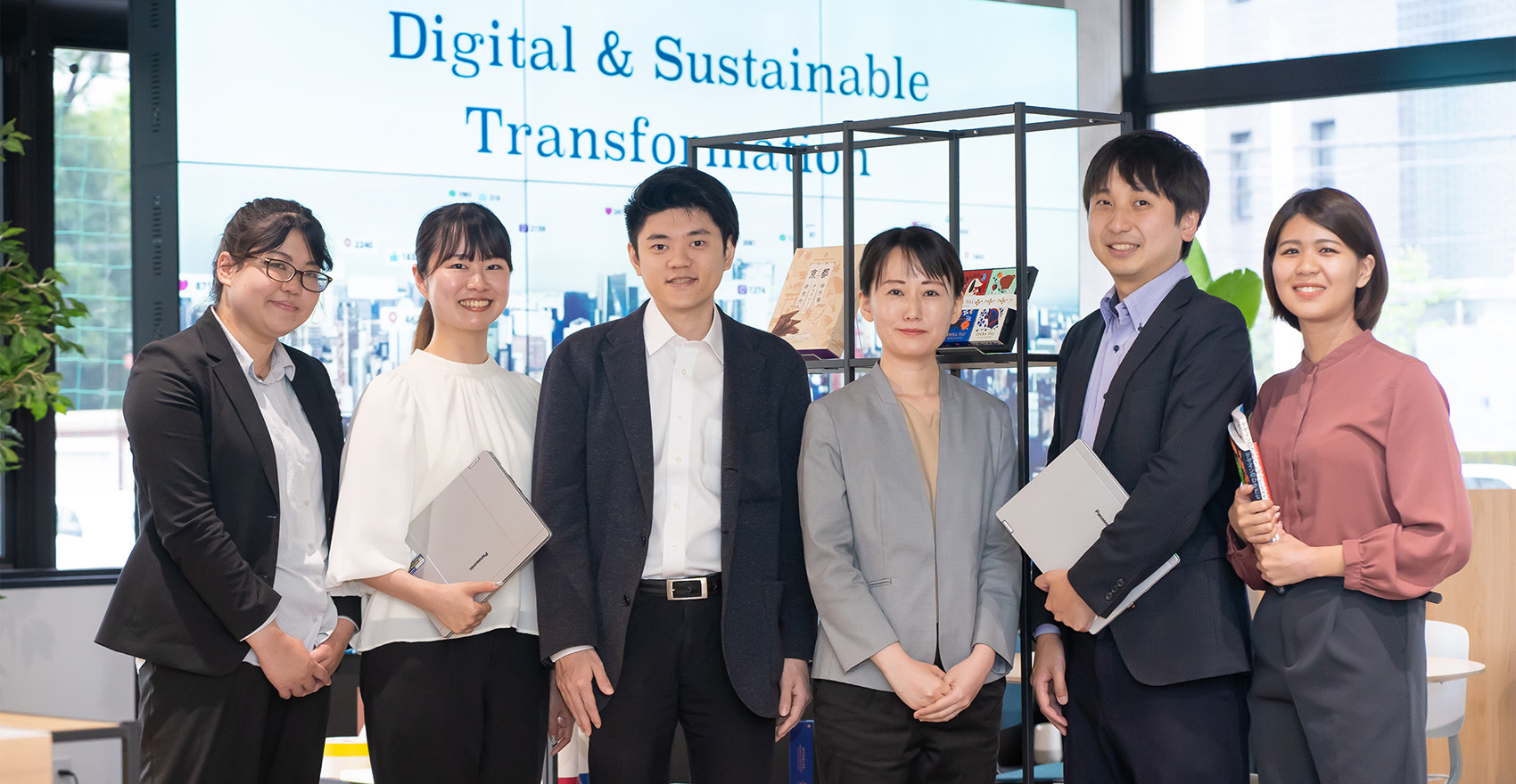 男性社員2名と女性社員4名が正面を向いて並んで笑顔をむける様子