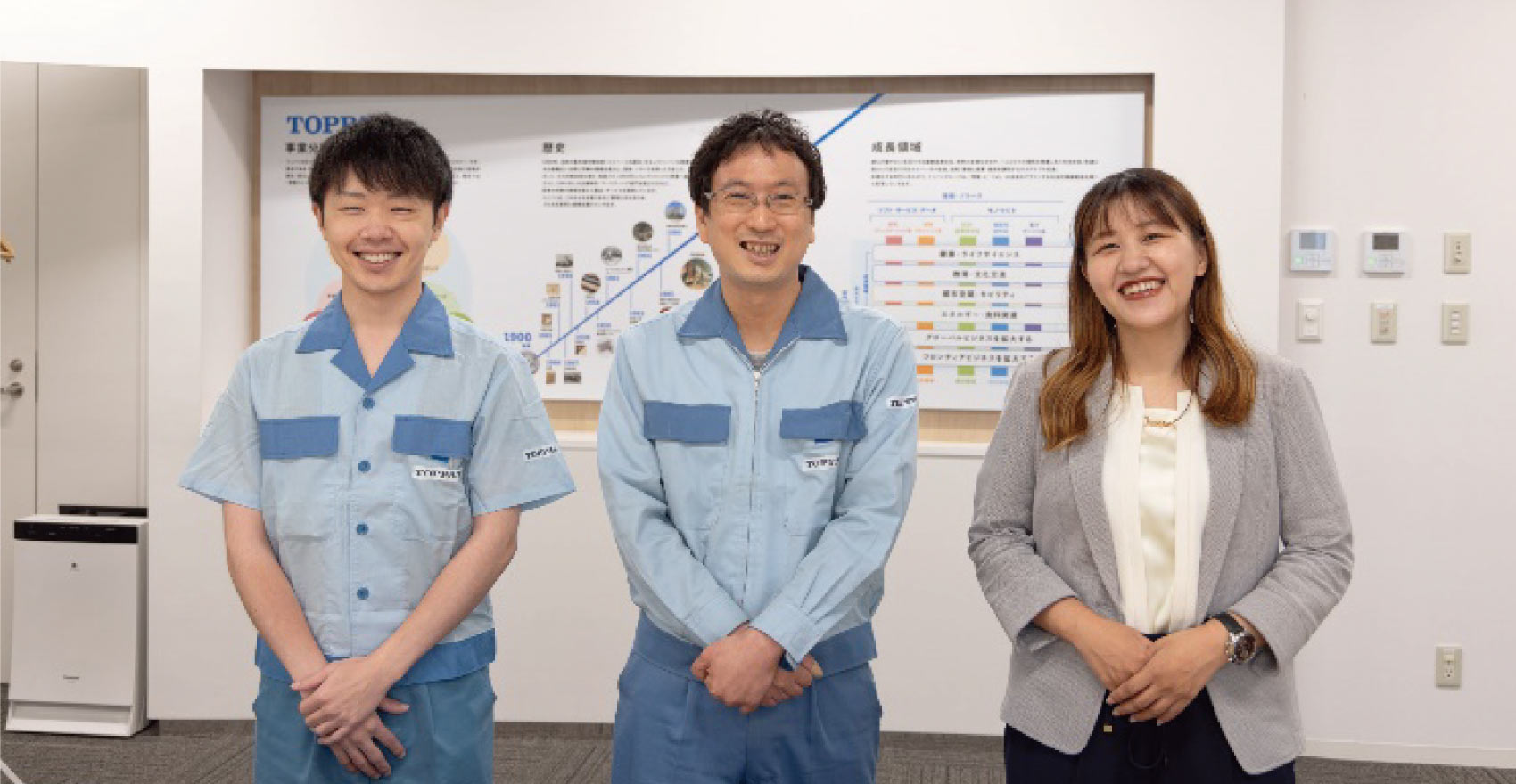 男性社員2名と女性社員1名が正面を向いて並んで笑顔をむける様子
