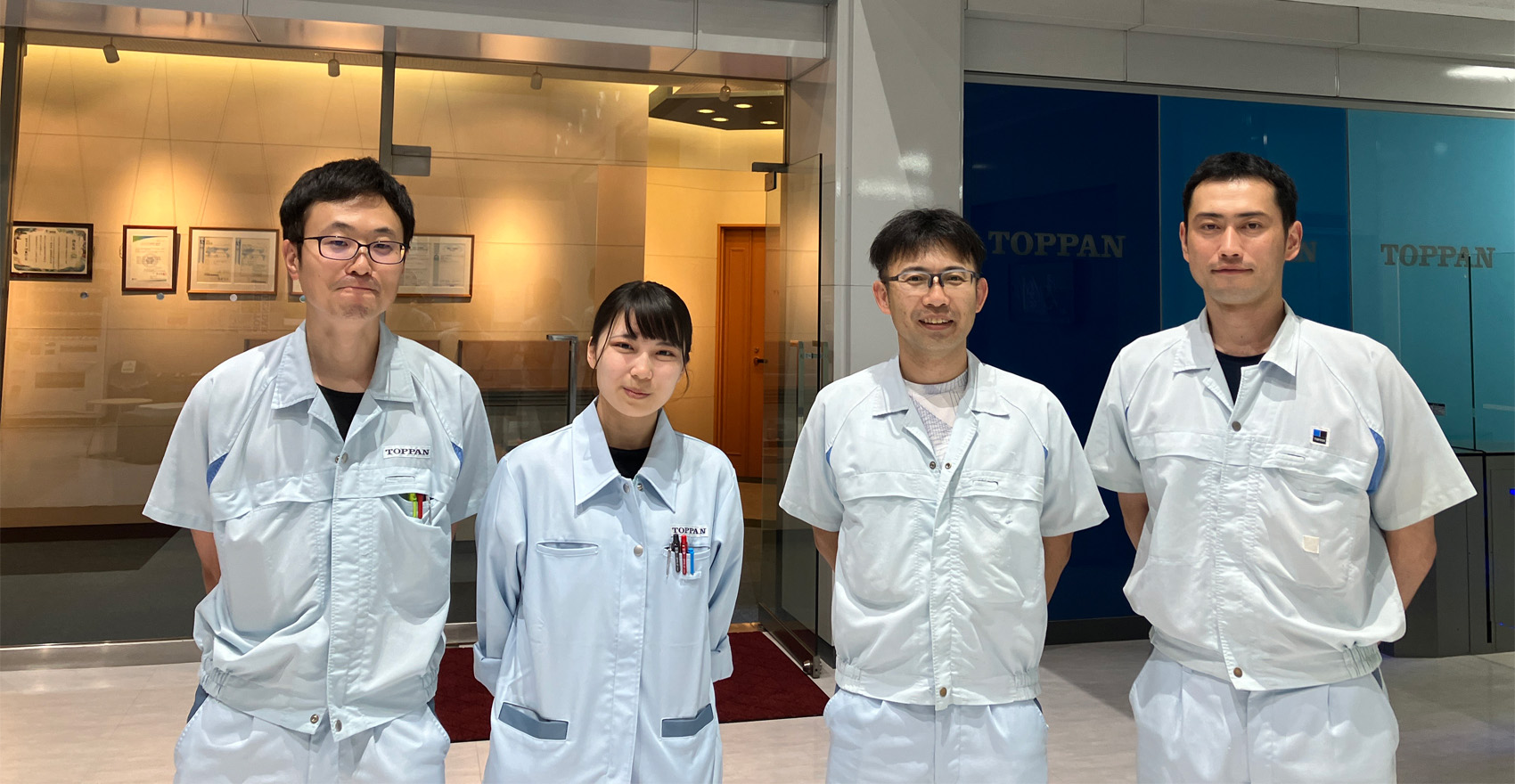 男性社員3名と女性社員1名が正面を向いて並んで笑顔をむける様子