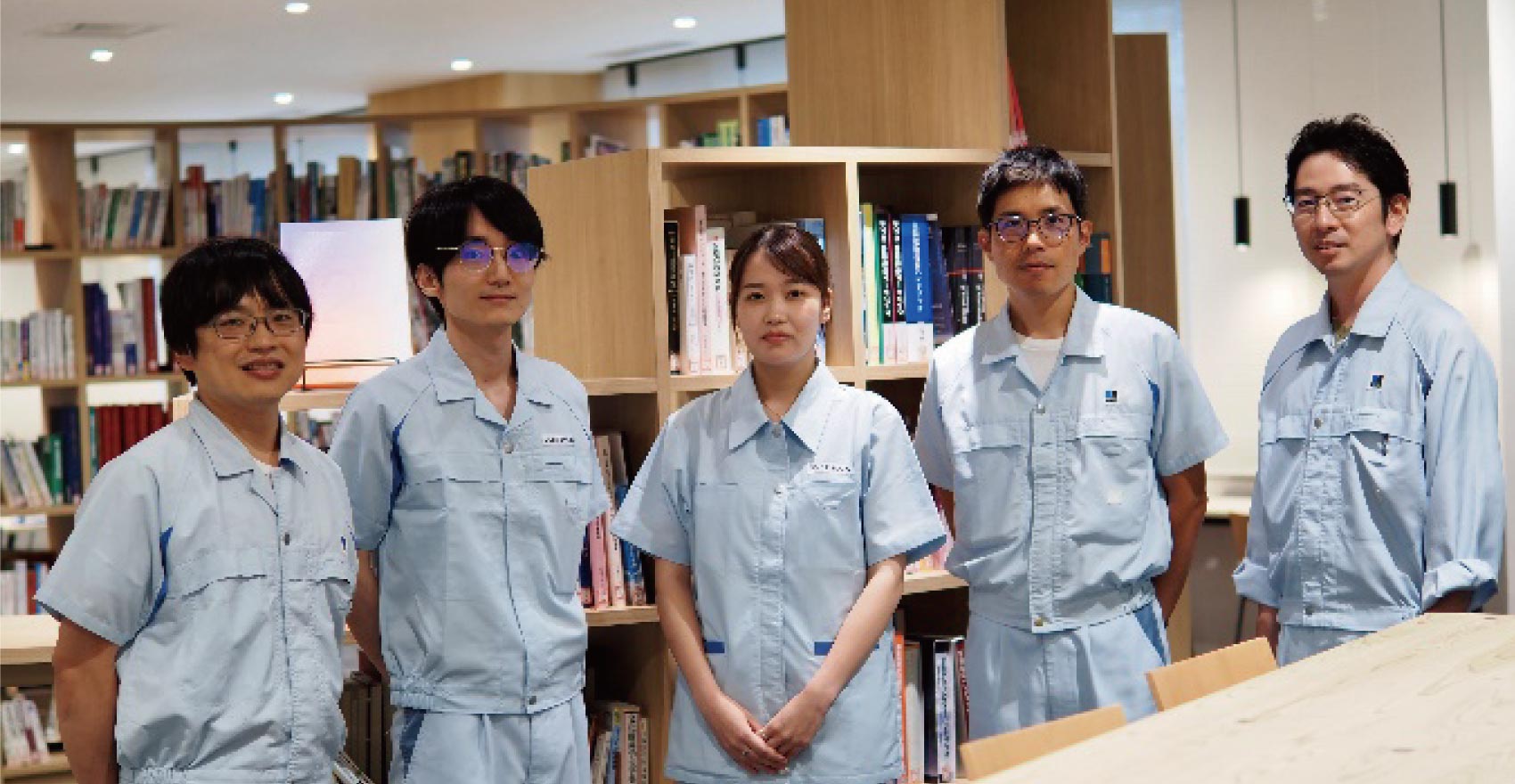 男性社員4名と女性社員1名が正面を向いて並んで笑顔をむける様子