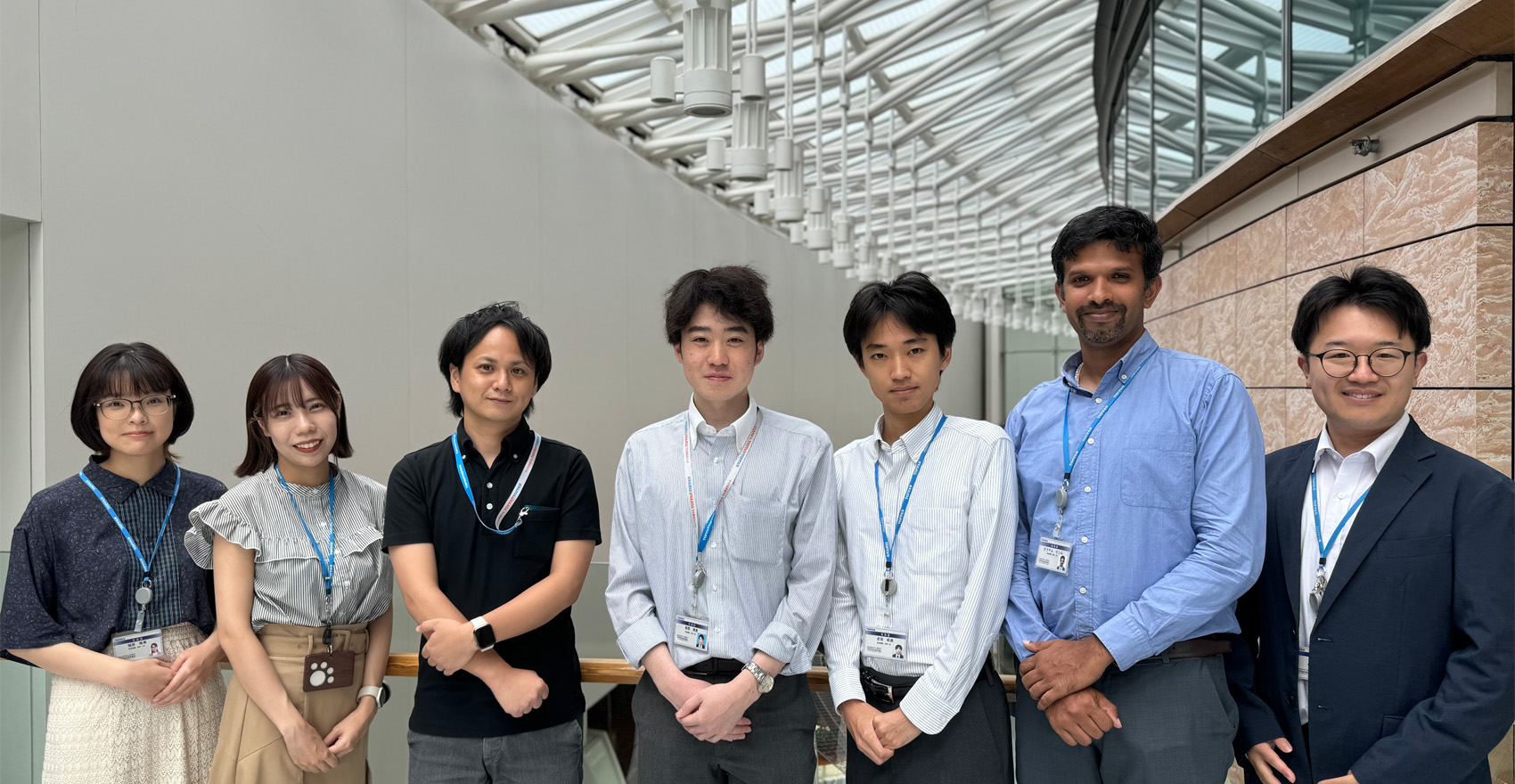 男性社員5名と女性社員2名が正面を向いて並んで笑顔をむける様子