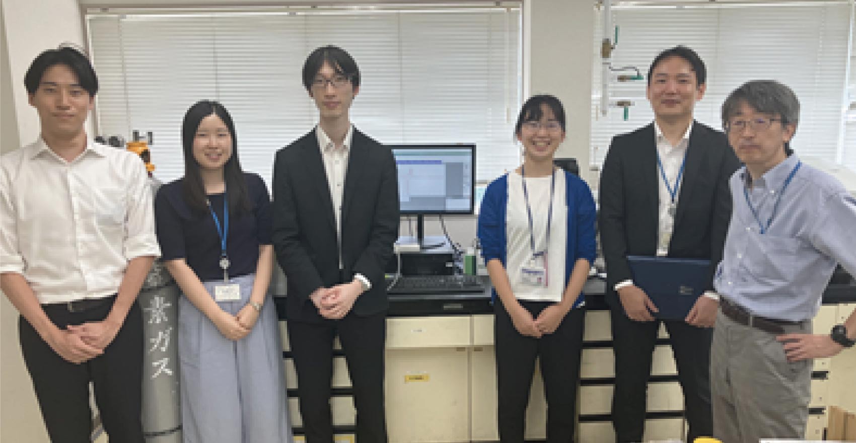 男性社員4名と女性社員2名が正面を向いて並んで笑顔をむける様子