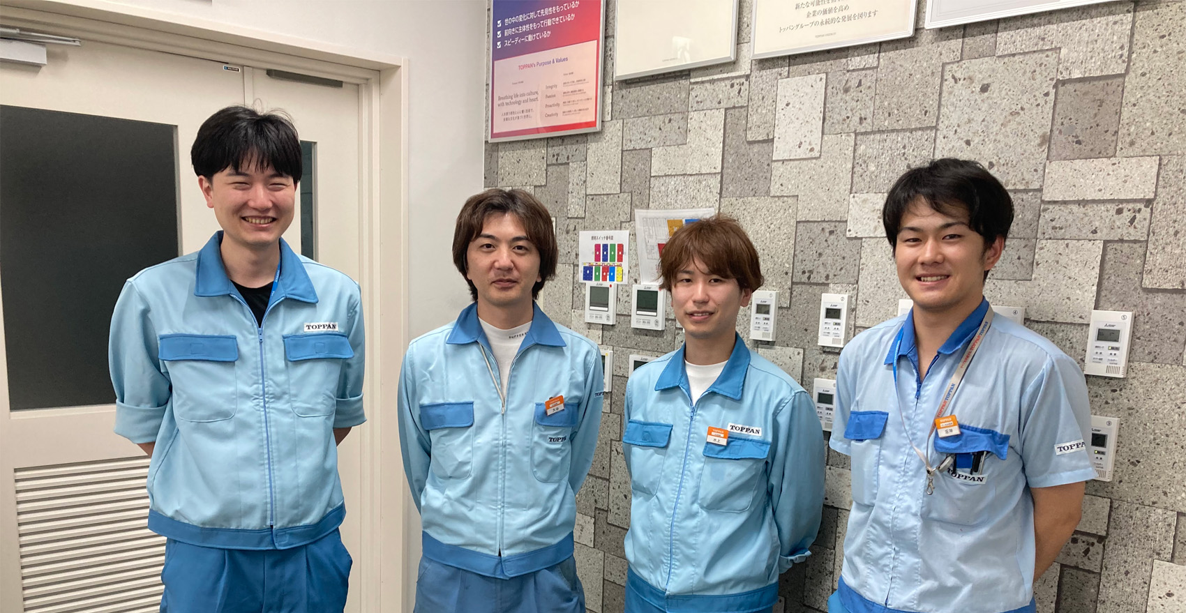 男性社員4名が正面を向いて並んで笑顔をむける様子