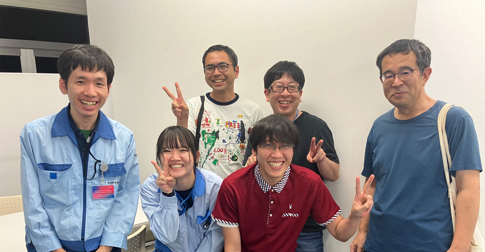 男性社員5名と女性社員1名が正面を向いて並んで笑顔をむける様子