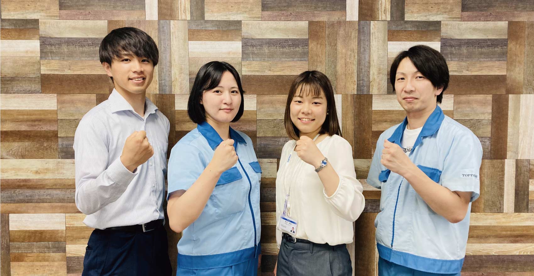 男性社員2名と女性社員2名が正面を向いて並んでガッツポーズをする様子